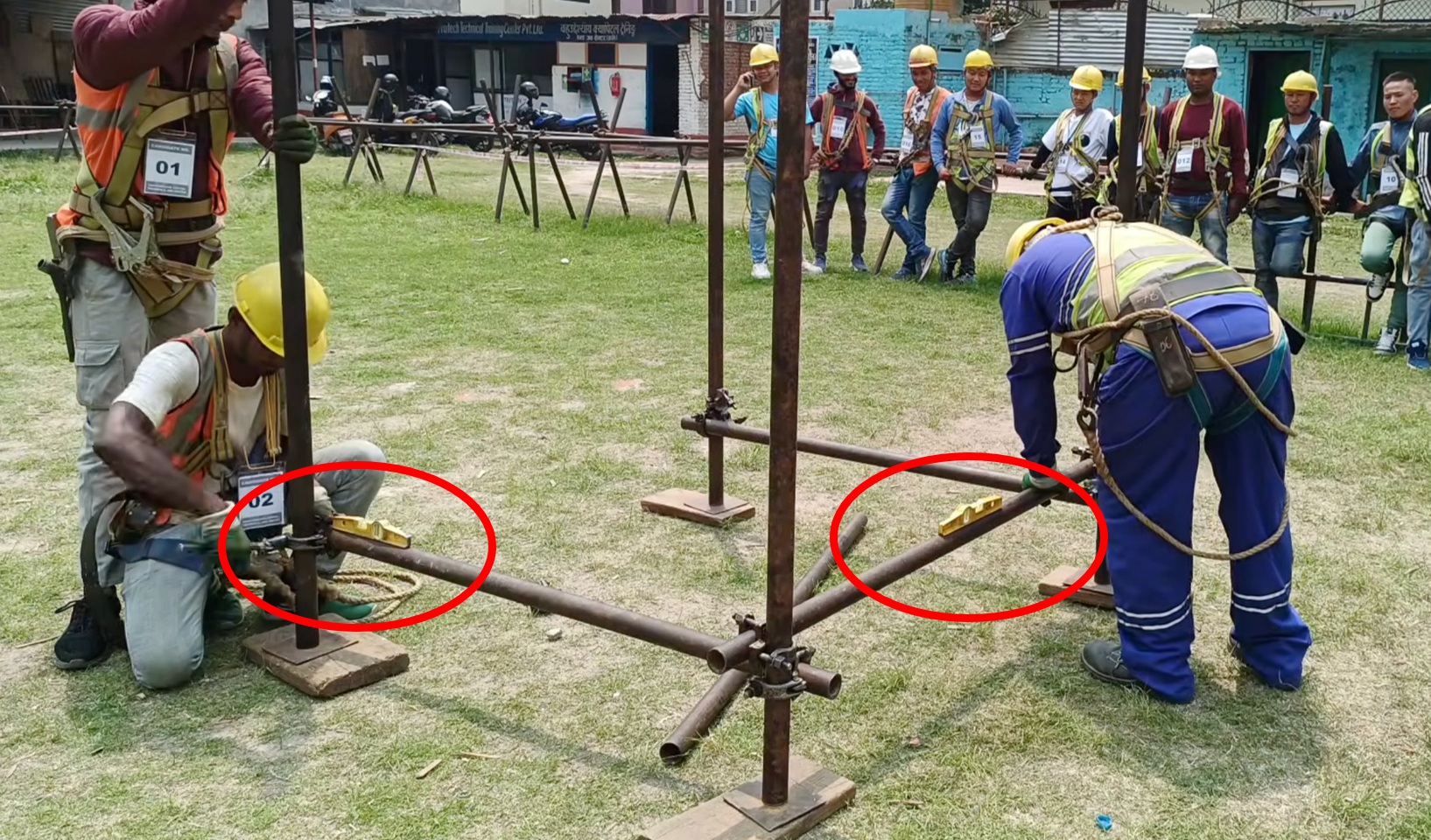 Scaffold workers correcting the alignment of a partially assembled structure with spirit levels